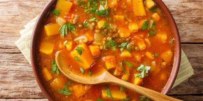 a bowl of stew with sweet potato, lentils, and leafy greens