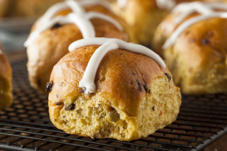 Close up of a few hot cross buns with frosted decorative cross on top.